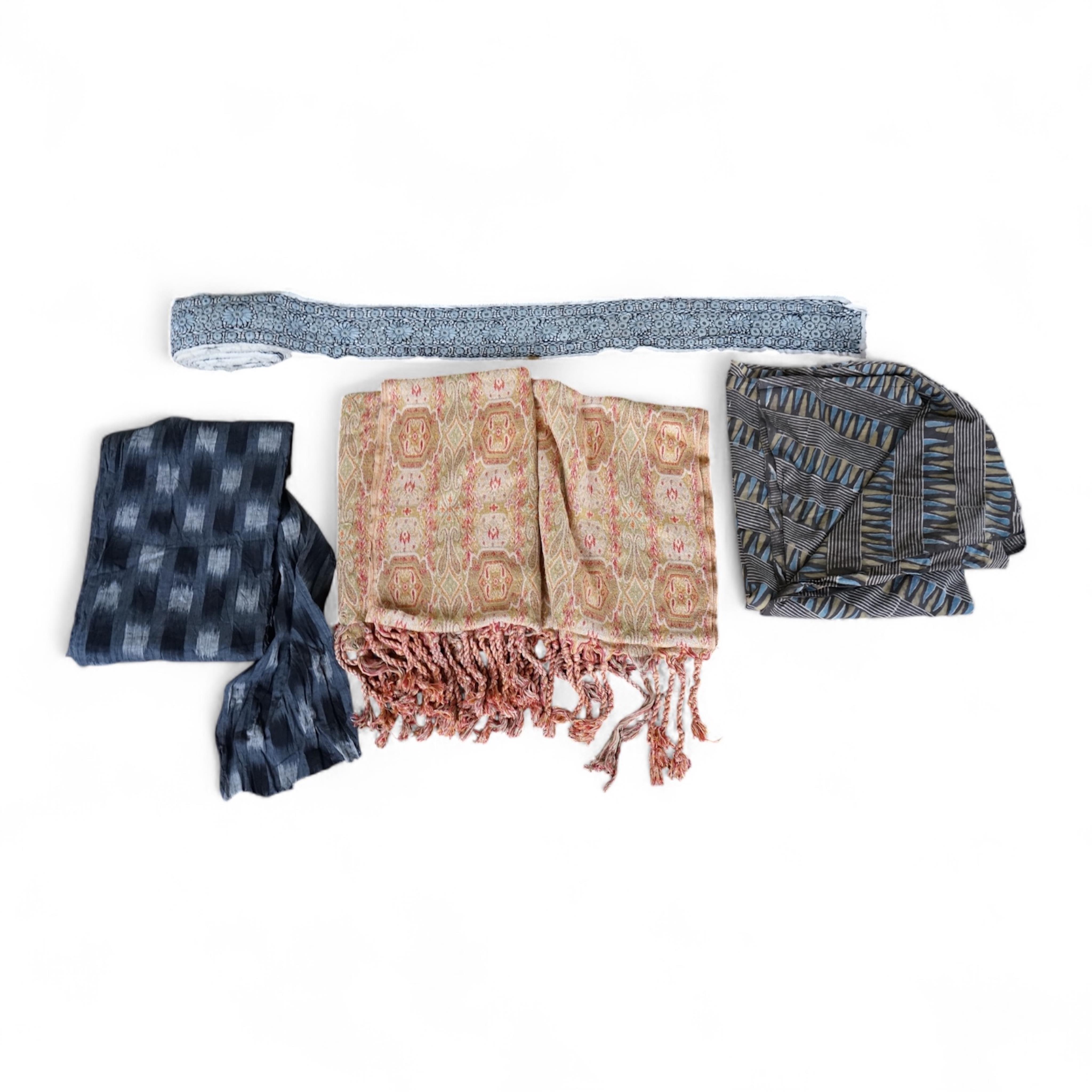 A long narrow length of grey Ikat woven fabric, a roll of Indian mirrored edging, a geometric batik printed length and a woven paisley ‘style’ tasselled stole. (4). Batik 392cm long x 108cm wide., Condition - good, all a